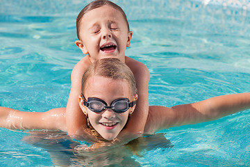 Image showing Two happy children playing on the swimming pool at the day time.