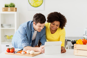 Image showing happy couple with tablet pc cooking food at home