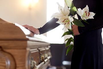 Image showing woman with lily flowers and coffin at funeral