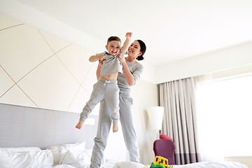 Image showing happy mother with son in bed at home or hotel room