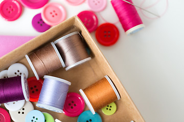 Image showing box with thread spools and sewing buttons on table