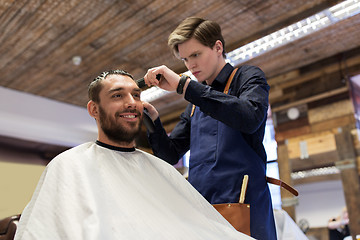 Image showing man and barber with trimmer cutting hair at salon