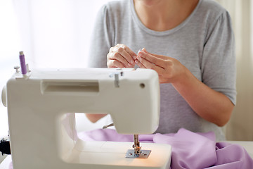 Image showing woman with spool of thread and sewing machine