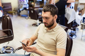 Image showing man with smartphone at barbershop or salon