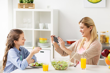 Image showing woman photographing daughter by smartphone at home