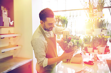 Image showing smiling florist man making bunch at flower shop