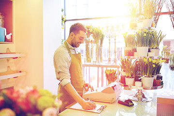 Image showing florist man with clipboard at flower shop counter