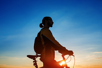 Image showing Silhouette of cyclist and a bike on sky background