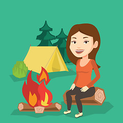 Image showing Woman sitting on log near campfire in the camping.