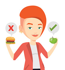 Image showing Woman choosing between hamburger and cupcake.