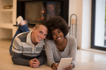 Image showing multiethnic couple using tablet computer on the floor