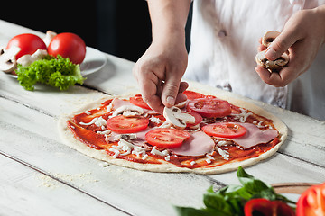 Image showing Closeup hand of chef baker in white uniform making pizza at kitchen