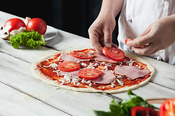 Image showing Closeup hand of chef baker in white uniform making pizza at kitchen