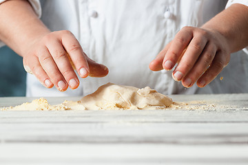 Image showing Closeup hand of chef baker in white uniform making pizza at kitchen