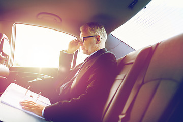 Image showing senior businessman with papers driving in car