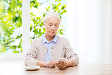 Image showing senior woman with smartphone texting at home