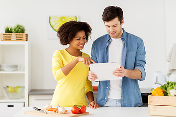 Image showing happy couple with tablet pc cooking food at home