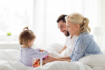 Image showing happy family with gift box in bed at home