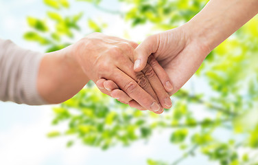 Image showing close up of senior and young woman holding hands