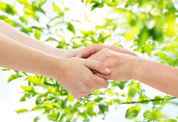 Image showing close up of senior and young woman holding hands