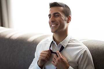 Image showing happy businessman taking off his tie at hotel room