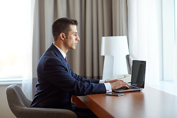 Image showing businessman typing on laptop at hotel room