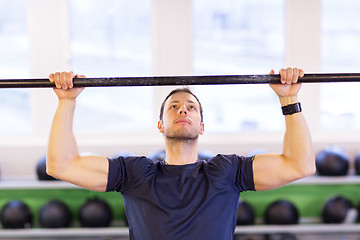 Image showing man exercising on bar and doing pull-ups in gym