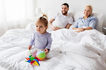 Image showing happy child with toys and parents in bed at home