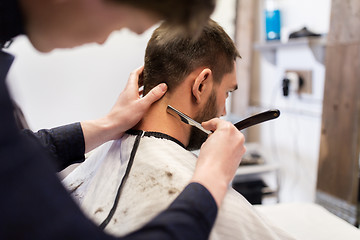 Image showing man and barber with straight razor shaving hair