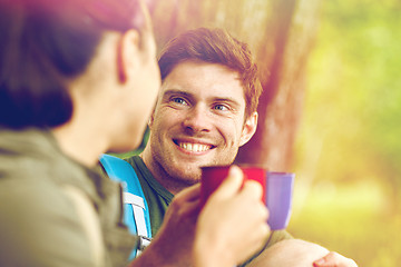 Image showing happy couple with cups drinking tea in nature