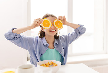 Image showing happy girl with orange having breakfast at home