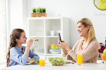 Image showing woman photographing daughter by smartphone at home