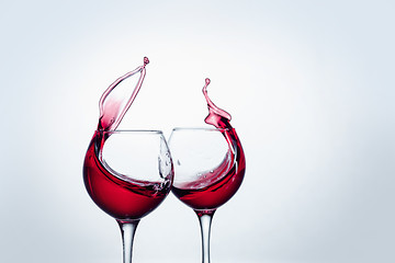 Image showing Two wine glasses in toasting gesture with big splashing.