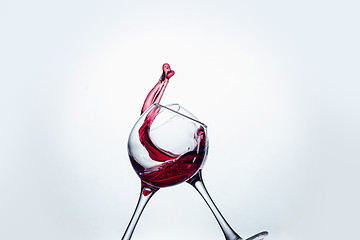 Image showing Two wine glasses in toasting gesture with big splashing.