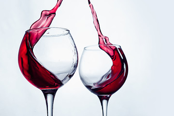 Image showing Two wine glasses in toasting gesture with big splashing.