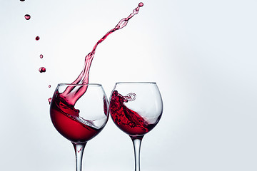 Image showing Two wine glasses in toasting gesture with big splashing.