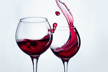 Image showing Two wine glasses in toasting gesture with big splashing.