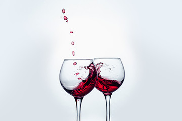 Image showing Two wine glasses in toasting gesture with big splashing.