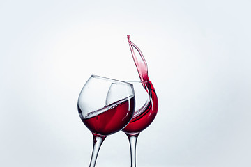 Image showing Two wine glasses in toasting gesture with big splashing.