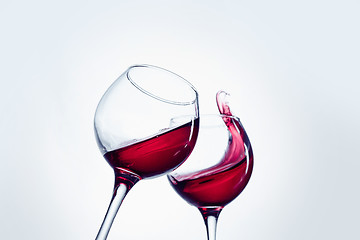 Image showing Two wine glasses in toasting gesture with big splashing.