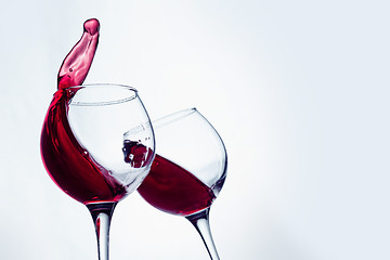 Image showing Two wine glasses in toasting gesture with big splashing.