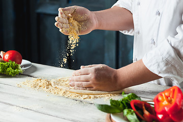 Image showing Closeup hand of chef baker in white uniform making pizza at kitchen