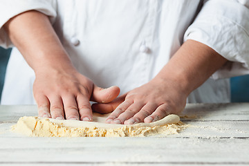 Image showing Closeup hand of chef baker in white uniform making pizza at kitchen