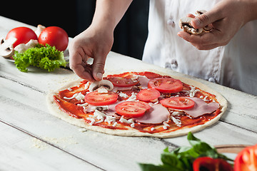 Image showing Closeup hand of chef baker in white uniform making pizza at kitchen