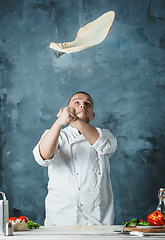 Image showing Closeup hand of chef baker in white uniform making pizza at kitchen