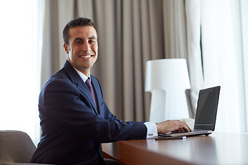 Image showing businessman typing on laptop at hotel room