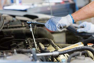 Image showing mechanic man with wrench repairing car at workshop