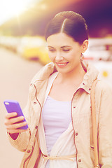 Image showing smiling woman with smartphone over taxi in city