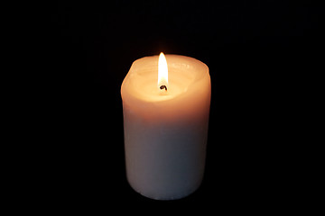 Image showing candle burning in darkness over black background