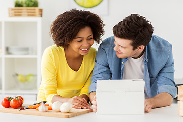 Image showing happy couple with tablet pc cooking food at home